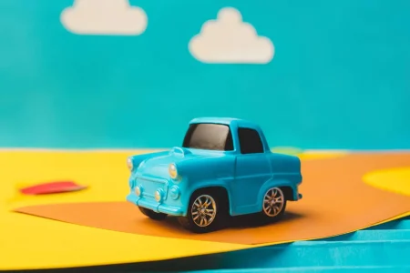 The toys - vintage miniature car on trendy colored paper. The pop art and creativity concept. The vacation, trip, travel, weekend, holidays concept